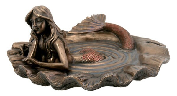 mermaid resting in pool of water inside of sea shell sculpture